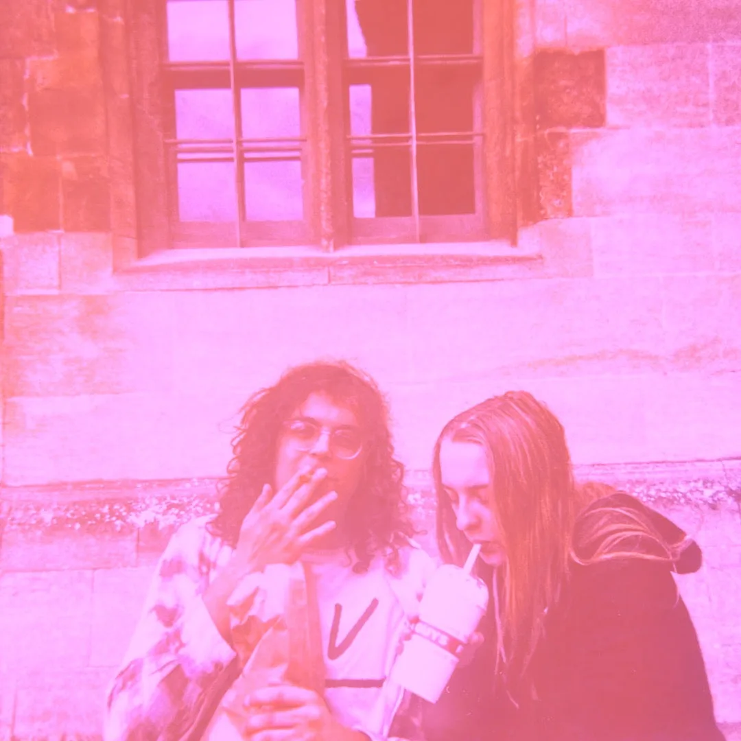 Two members of pedal partners in front of a stone building with a sash window